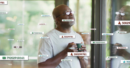 Gazing senior man wearing eyeglasses holding mug in modern lounge with floating digital data tags....