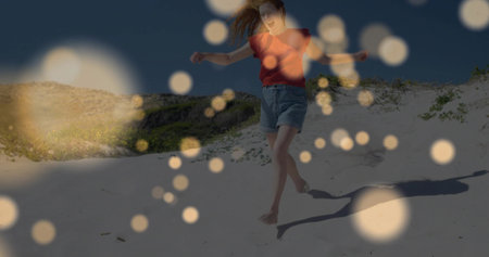 Skipping woman in red top and denim shorts crossing sand dune at twilight, with soft bokeh. Adventure, leisure, outdoor, scenic, tranquil, lifestyle, minimalismの写真素材