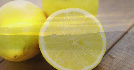 Displaying halved lemon revealing juicy pulp on kitchen tabletop, with two whole lemons. Citrus,...