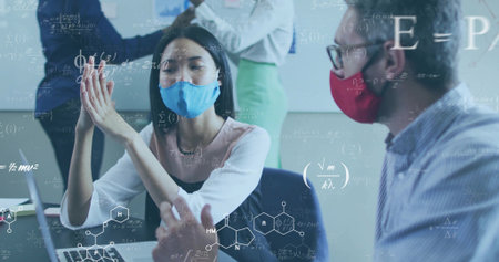Gesturing Asian researcher wearing pink blouse and blue mask at conference room table, with laptop. Collaboration, teamwork, education, innovation, professional, academic, scienceの写真素材