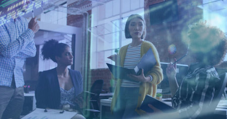 Presenting woman leading team meeting in open-plan office, with open binder and monitors. Collaboration, brainstorming, teamwork, productivity, modernity, communication, professionalの写真素材