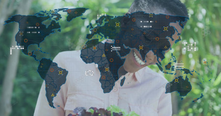 Gardener holding seedling container in garden, map overlay showing data icons. Urban, botanical, vibrant, eco-friendly, modern, innovation, sustainabilityの写真素材