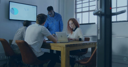Meeting four professionals reviewing documents at table in conference room, with laptop and display. Collaboration, teamwork, brainstorming, digitaltools, professionalenvironmentの写真素材