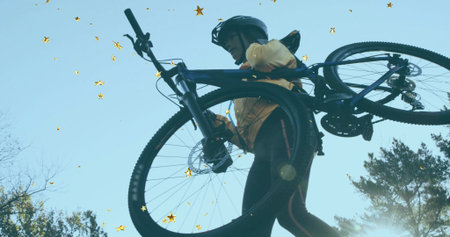 Hoisting cyclist lifting mountain bike overhead on trail, wearing reflective leggings and helmet....