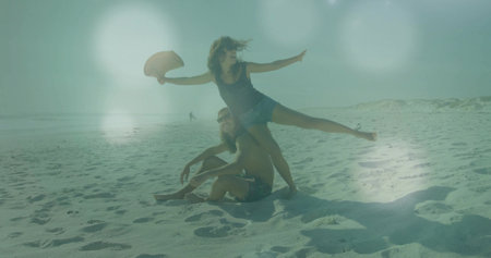 Balancing woman on shoulders of man sitting on sandy ocean beach, with wide-brimmed sun hat. Beach, leisure, summer, carefree, relaxation, scenic, outdoorsの写真素材