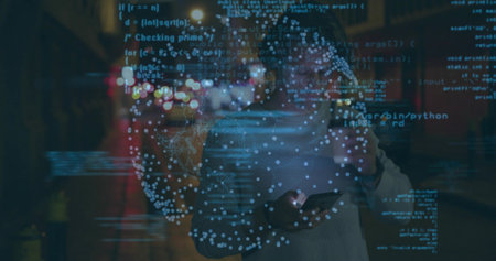 Holding smartphone, European man wearing sweater standing on street at night, with code overlay....