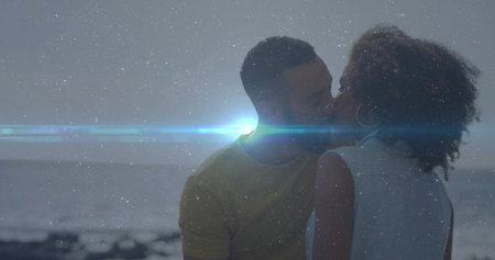 Sharing kiss, romantic couple embracing on rocky shoreline at dusk, with bright lens flare. Romance, intimacy, connection, serenity, dusk, landscape, emotionalの写真素材