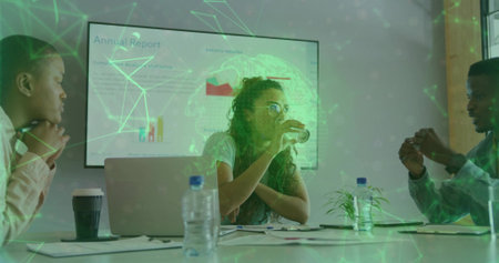 Woman wearing glasses sipping water while collaborating in conference room, with laptops and charts....