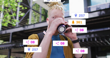 Drinking man in mustard jacket raising mug at urban plaza, with backpack and floating digital icons....