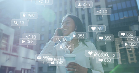 Smiling Asian woman in business wear holding smartphone and coffee on city street with social icons. Urban, professional, vibrant, communication, modern, networking, lifestyleの写真素材