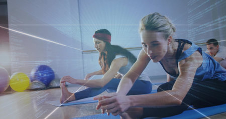 Woman in blue tank top stretching forward on yoga mat in yoga studio, with exercise balls. Fitness, wellness, flexibility, mindfulness, studio, athletic, modernの写真素材