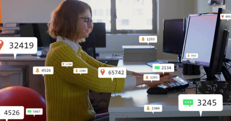 Typing green-sweatered woman in office at desk on red exercise ball, with notification bubbles. Modern, professional, ergonomic, digital, productivity, innovation, vibrantの写真素材