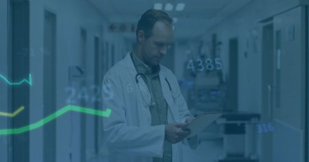 Holding tablet doctor wearing lab coat and stethoscope viewing digital graphs in hospital hall....