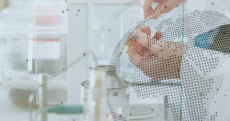 Latex-gloved researcher in lab coat pipetting liquid into container in lab, with dotted partition....