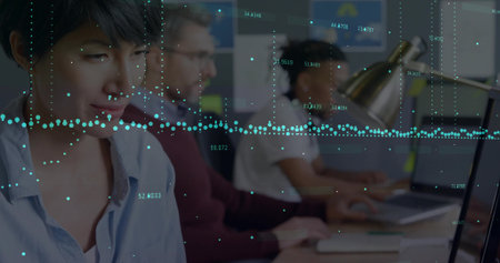 Working Asian woman typing on laptop at office desk with metallic lamp, data graphs, copy space. Collaboration, innovation, technology, professionalism, teamwork, modern, analyticsの写真素材