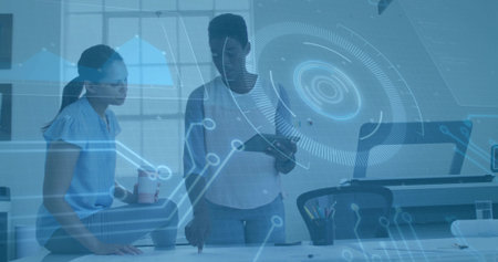 Collaborating women reviewing project at office desk, with tablet and coffee cup amid tech overlay. Teamwork, innovation, productivity, modernity, communication, workspace, digitalの写真素材