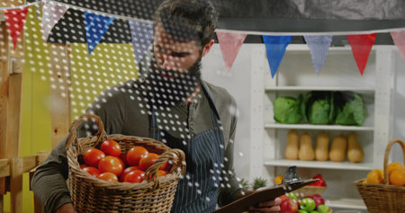 Vendor wearing apron holding basket of tomatoes and clipboard at market stall with bunting. Farmer,...