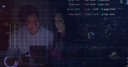 Two colleagues in business attire examining tablet in office at night with overlays on cityscape. Corporate, analytics, modern, technology, finance, professional, urbanの写真素材