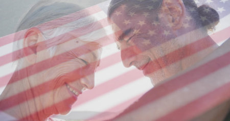 Leaning foreheads together mature mother and son smiling in studio, with American flag overlay....