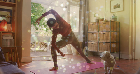 Stretching woman in maroon top holding dumbbell on yoga mat in living room, with dog. Wellness, tranquility, home fitness, interior design, mindfulness, relaxation, healthy lifestyleの写真素材