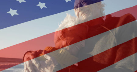 Smiling senior couple hugging on sandy shoreline, wearing knit sweater and scarf. Senior, couple, beach, coastline, tranquility, leisureの写真素材