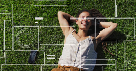Lying woman wearing striped top, brown pants on grass, showing wristwatch and smartphone overlay. Nature, relaxation, leisure, outdoor, technology, connectivity, casualの写真素材