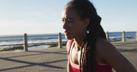 Leaning forward runner catching breath on promenade by ocean waves and metal railing, copy space....