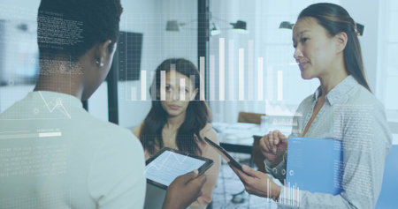 Collaborating businesswomen analyzing data in office meeting room, with tablets and hologram charts. Business, teamwork, innovation, technology, analytics, corporate, presentationの写真素材
