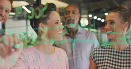 Four professionals studying green waveforms on glass partition in office, using dry-erase marker. Innovation, teamwork, analytics, modern, collaboration, communication, technologyの写真素材