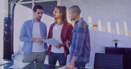 Three male colleagues discussing printed charts in modern conference room, with projected bar graph. Collaboration, teamwork, professional, urban, innovation, brainstorming, modernの写真素材