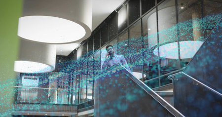 Talking man in business shirt holding smartphone to ear on staircase in lobby, with digital overlay. Corporate, professional, futuristic, networking, technology, modern, urbanの写真素材
