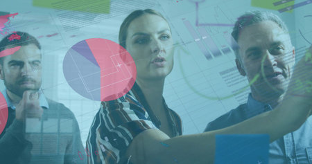 Presenting woman wearing striped blouse pointing at digital chart display in office with pie charts. Data analytics, teamwork, corporate, digital interface, modern design, business strategyの写真素材