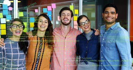 Standing colleagues celebrating in tech office with glass wall showing sticky notes, code snippets. Collaboration, teamwork, innovation, modern, startup, vibrant, professionalの写真素材