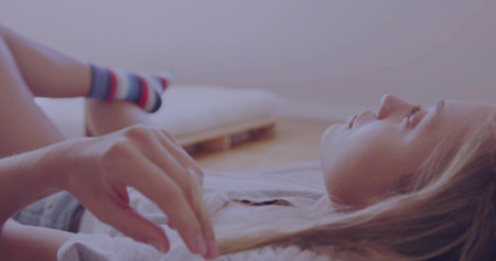 Lying female wearing denim shorts and striped socks on wood floor, with pallet frame, thin mattress. Minimalist, relaxation, cozy, casual, contemporary, lifestyle, comfortableの写真素材