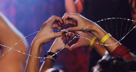Forming four hands into heart shape at concert hall, with wristbands, bracelets and stage lights. Celebration, unity, diversity, festival, enthusiasm, energy, vibrantの写真素材