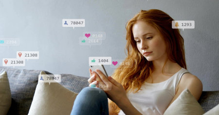 Scrolling woman checking smartphone at home on sofa cushions with notification icons, copy space. Technology, lifestyle, modern, relaxation, leisure, digital, casualの写真素材