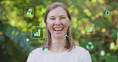 Smiling woman wearing sweater in garden with bar-chart, droplet, turbine, CO and recycling icons. Environmental awareness, sustainability, eco-friendly, renewable energy, conservation, natureの写真素材