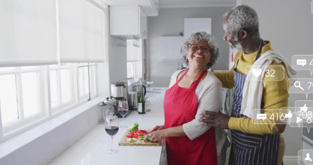 Slicing tomatoes, senior woman and man cooking in home kitchen, with cutting board and wine glass. Cooking, culinary, domestic, cozy, health, celebration, familyの写真素材