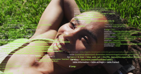 Lying woman wearing yellow tank top on grassy lawn, displaying smartwatch and computer code overlay. Relaxation, outdoor, technology, nature, vitality, leisure, tranquilityの写真素材
