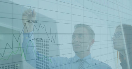 Mature businessman drawing and analyzing line graphs on glass board in modern office, copy space....
