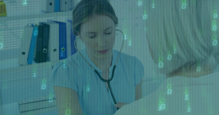 Doctor in scrub top listening to patient with stethoscope in clinic, with binders and code overlay. Healthcare, digital, professionalism, consultation, technology, medical, examinationの写真素材