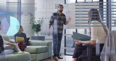Pointing man presenting chart display in office area, with yellow notebook, laptop and green folder. Business, collaboration, professional, startup, teamwork, modern, corporateの写真素材