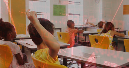 Raising hand Asian boy wearing yellow shirt, sitting on chair with paper in classroom, copy space. Classroom, students, education, learning, youth, school, studyの写真素材