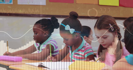 Writing students using yellow pencils in notebooks on desks in classroom, with cork bulletin board. Education, learning, school, childhood, concentration, creativity, teamworkの写真素材