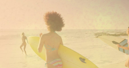 Heading three surfers in swimsuits carrying yellow, white-blue surfboards toward ocean on wet sand. Adventure, outdoor, vibrant, fitness, leisure, coastal, activityの写真素材