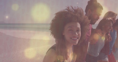 Walking curly-haired woman guiding friends along sandy beach in casual shorts and tops, copy space....