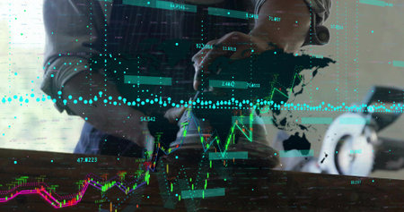Tying sneaker laces, man sitting at wooden table with laptop, 3D stock charts overlaying world map....