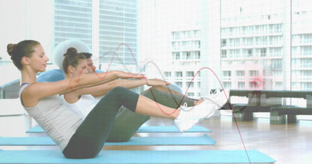 Three adults performing V-sit exercise on blue mats in fitness studio, wearing workout clothes....