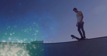 Balancing skateboarder wearing tee leaning on ramp at skatepark with skateboard, flares, copy space. Urban, extreme sports, vibrant, athleticism, outdoor, dynamic, youthfulの写真素材