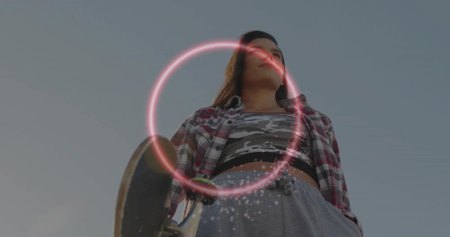 Holding skateboard, skateboarder wearing plaid shirt standing in urban space, with neon ring effect....